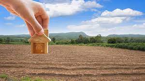 Indian couple examining a land layout map with a real estate agent on a plot site